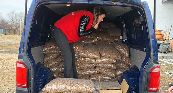 A volunteer helps to stack bags of food in the back of a van.