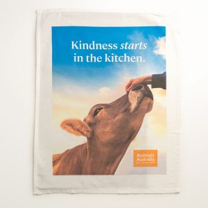 Tea towel with an image of a hand patting a cow's nose, orange AA logo and the words 'Kindness starts in the kitchen.'
