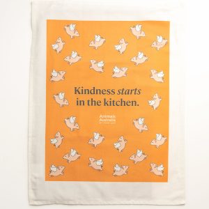 Orange tea towel with white AA logo, flying pigs and 'Kindness starts in the kitchen.'