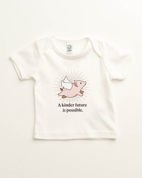 White baby tee with pic of a flying pig on it and the phrase 'A kinder future is possible.'
