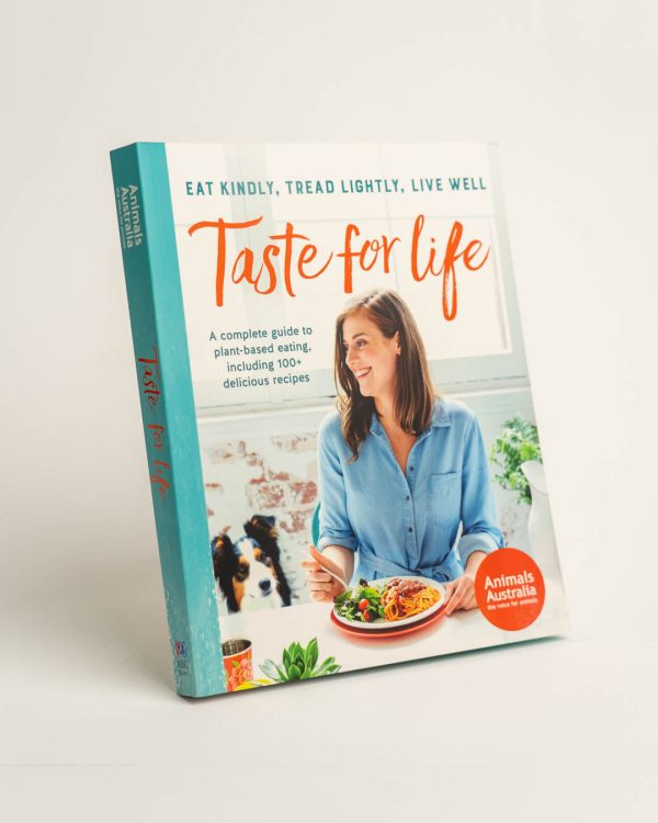 Front cover of 'Taste for Life' cookbook. Image of a person eating with a dog sitting by their side
