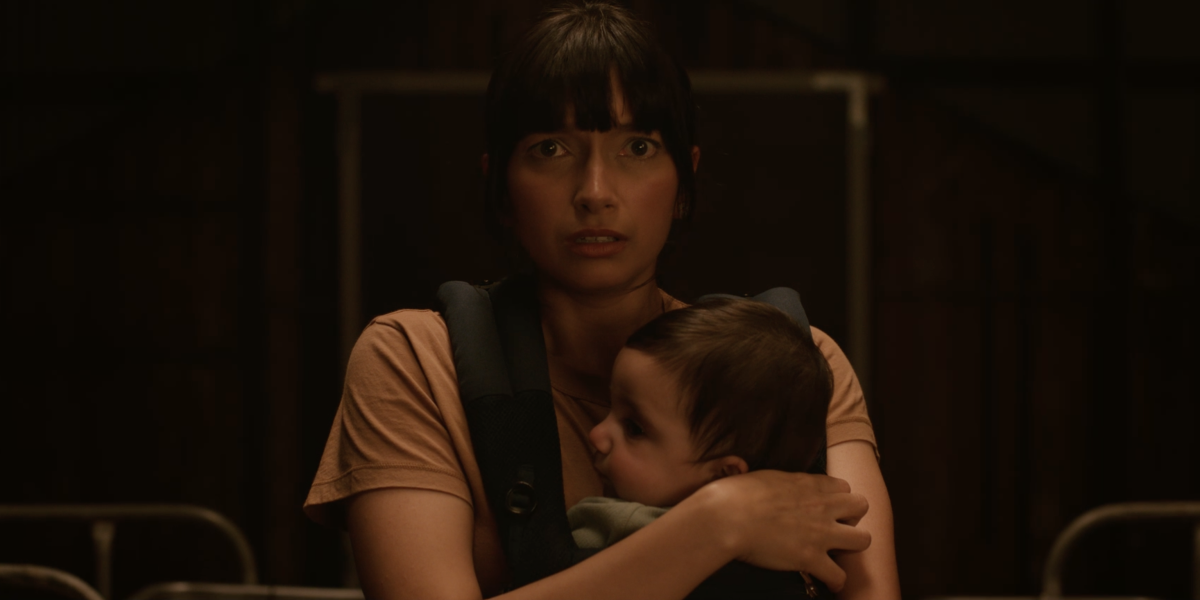 Woman holding baby looking at camera, worried look on her face.