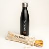 Black drink bottle with 'Be kind' and the AA logo. Reusable bamboo cutlery set with straw and straw cleaner is lying in front of the bottle in it's carry pouch printed with 'Eat kindly.' and the AA logo
