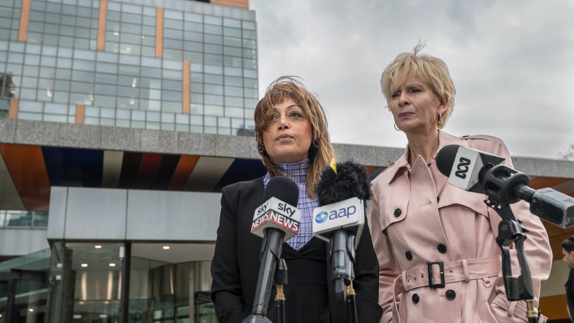 Lyn White and Shatha Hamade represent animals at Federal Court, news microphones are in front of them.