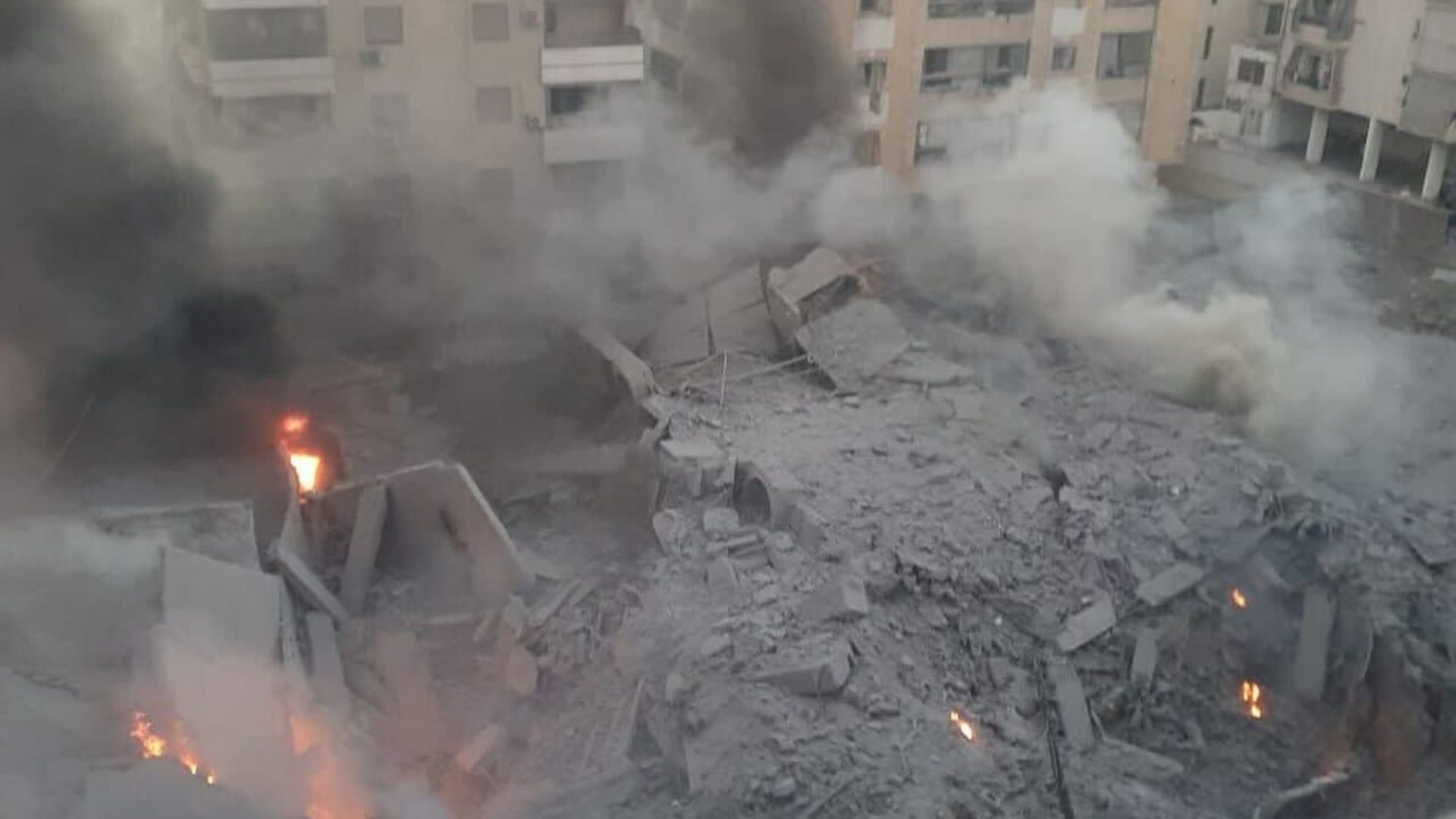 Rubble from a bombed building burns and smokes