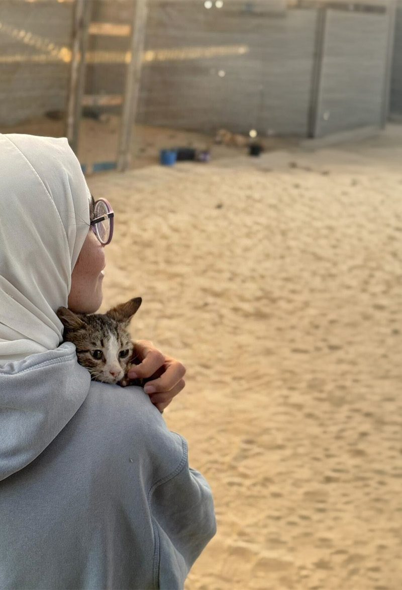 A woman holds a kitten to her chest.