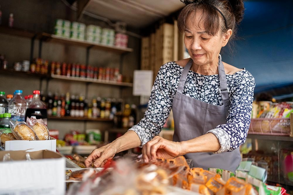 A woman in an Asian Grocery Store sorts through stock.