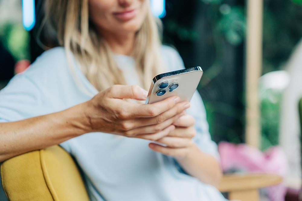 A woman scrolls through the phone she is holding.