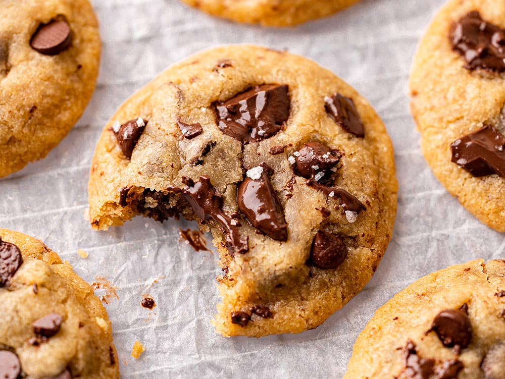 A close-up of a freshly baked choc chip cookie with a bite taken out. 