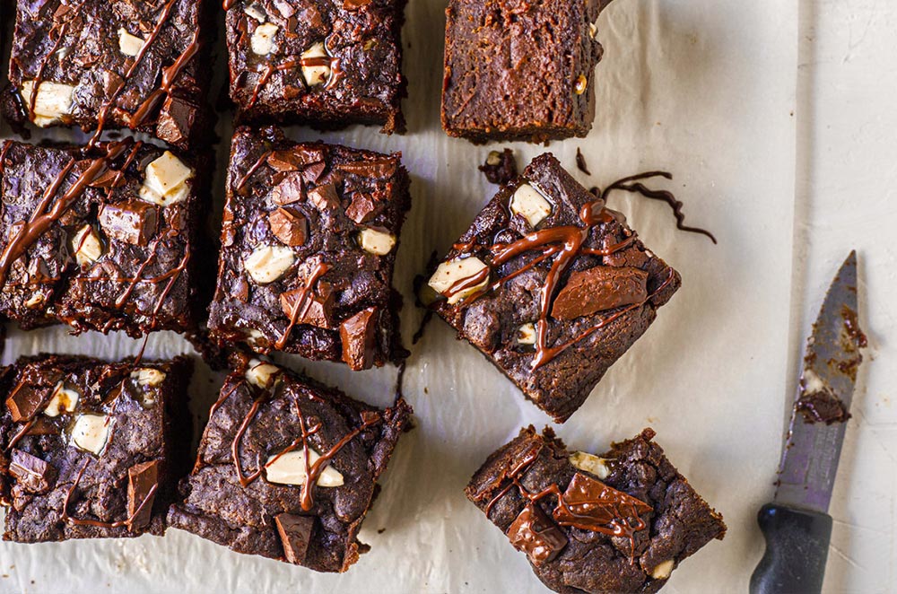 An overhead view of homemade brownie cut into squares. One has a bite taken out. 