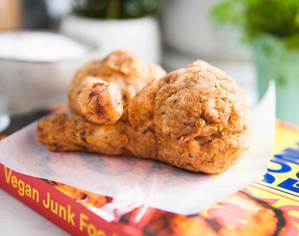 Two jackfruit 'chicken' drumsticks are laid on parchment paper.