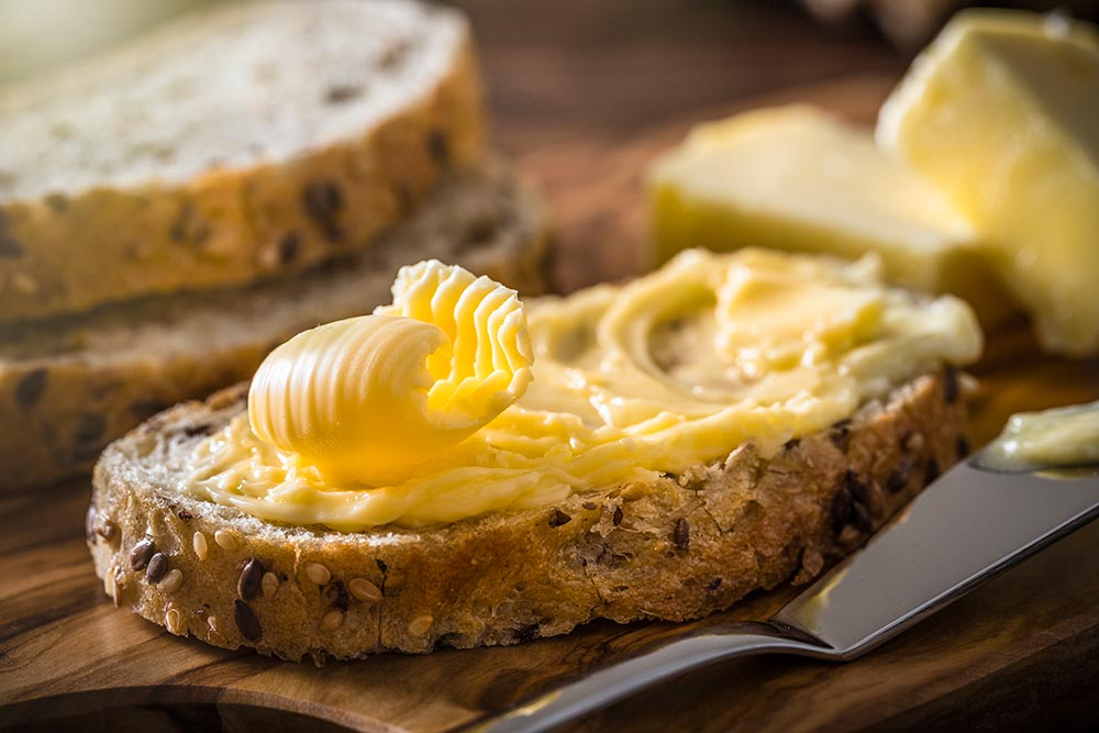 A piece of bread with a delicate curl of butter on top.