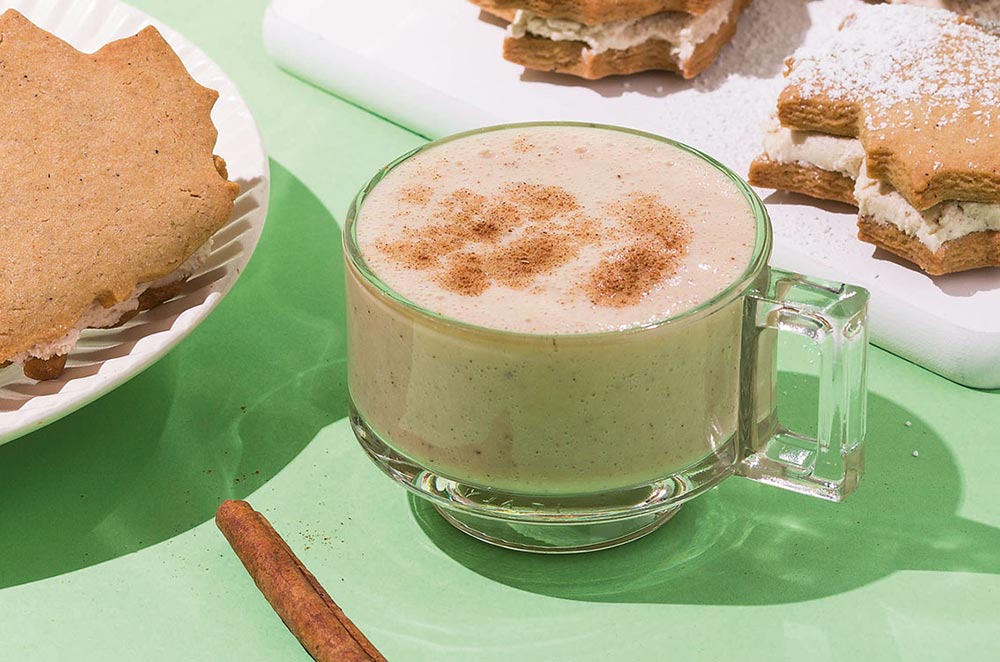 A small clear glass cup filled with vegan eggnog, decorated with a sprinkling of nutmeg. 