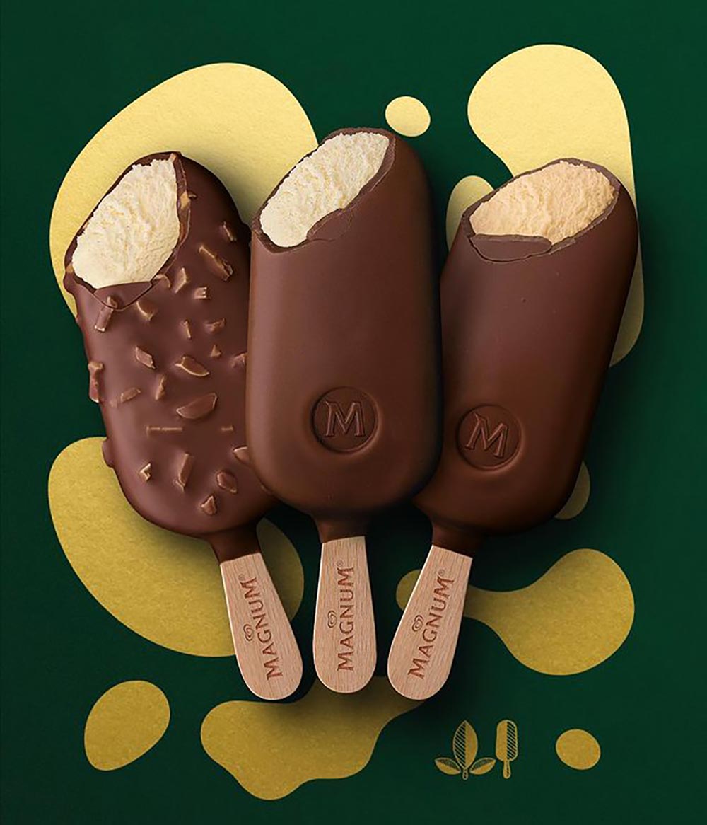 Three Magnum ice creams over a green and gold background. Each ice cream stick has a bite taken out of it revealing each of the three plant-based flavours. 