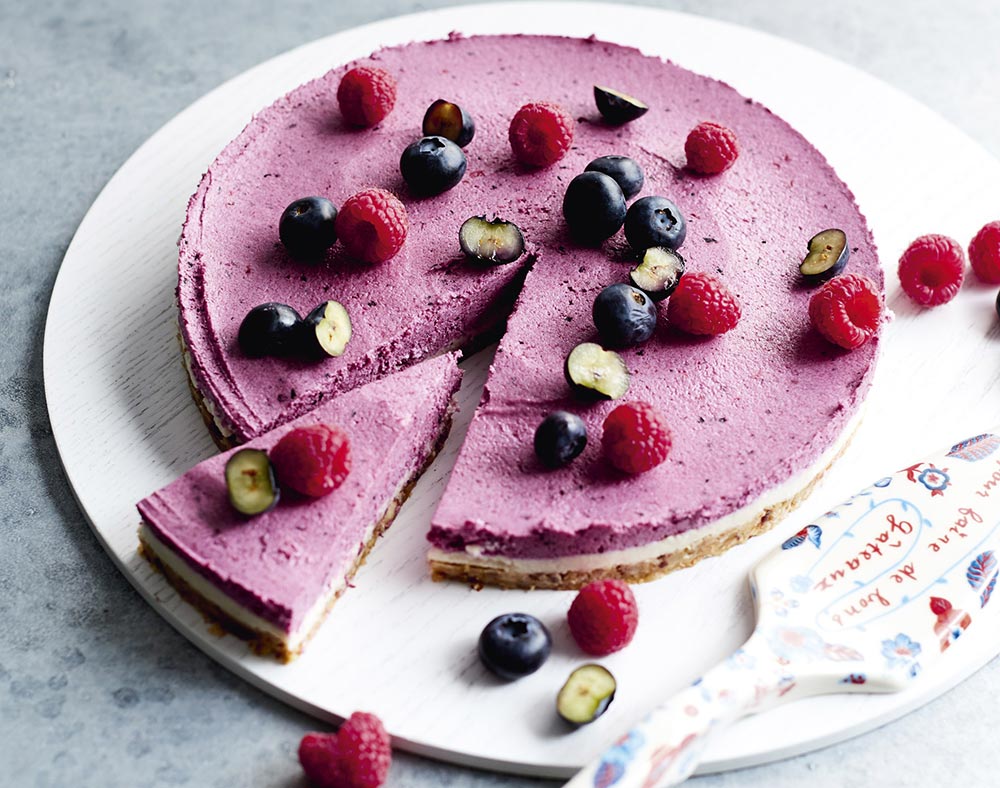 A vibrant purple cheesecake topped with fresh berries.