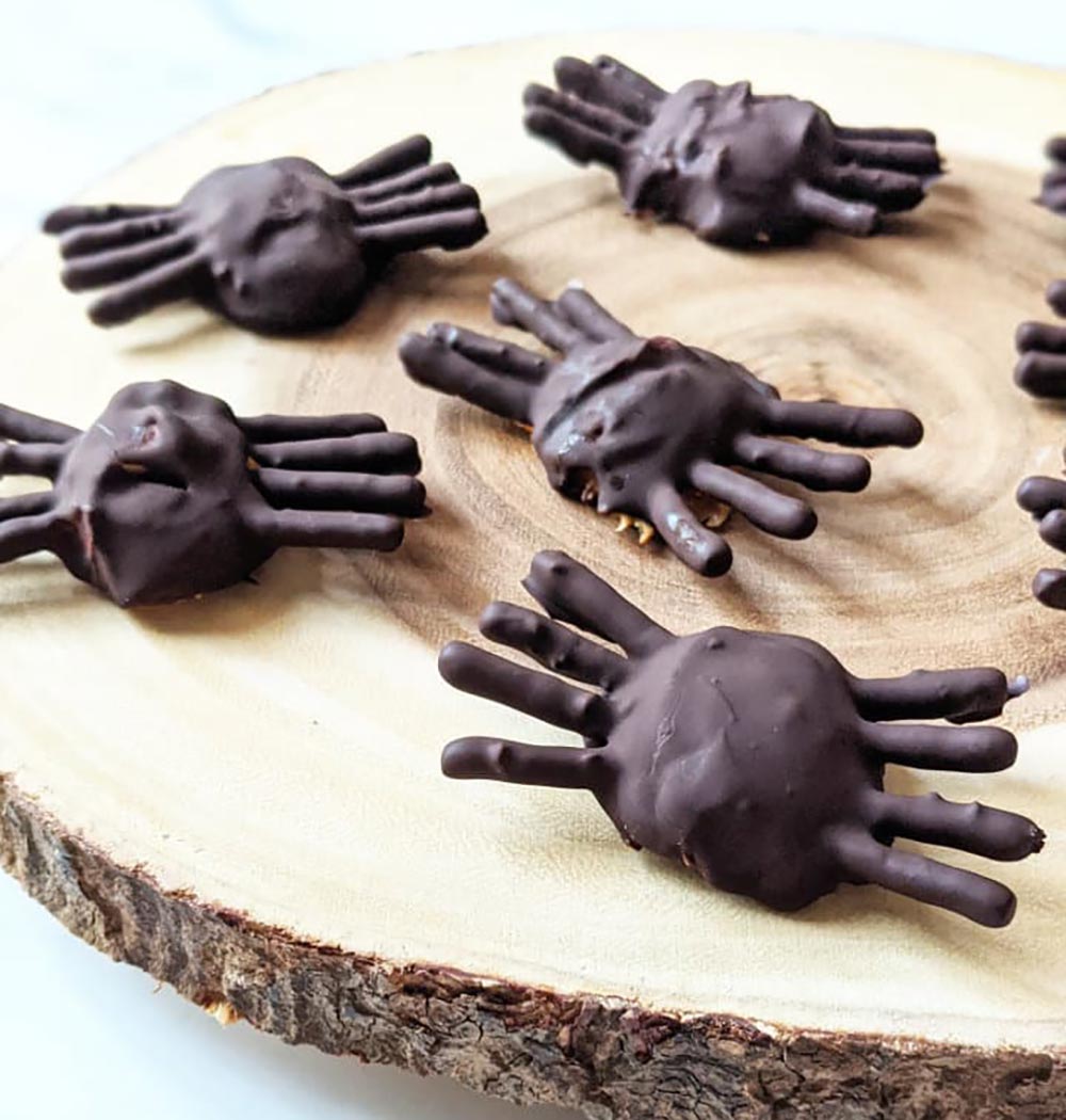 Chocolate-covered spider treats sit on a wooden board.