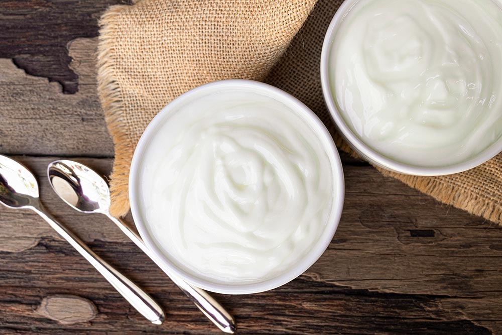 Two small bowls of plant-based yoghurt on a wooden table.