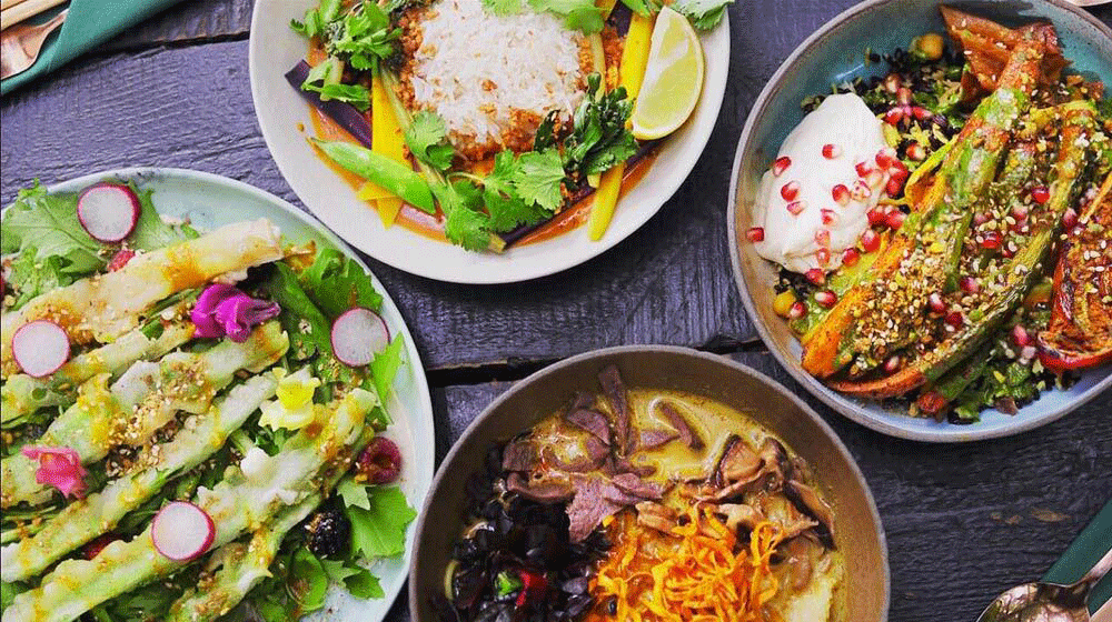 Overhead view of plates full of vegetable dishes. 