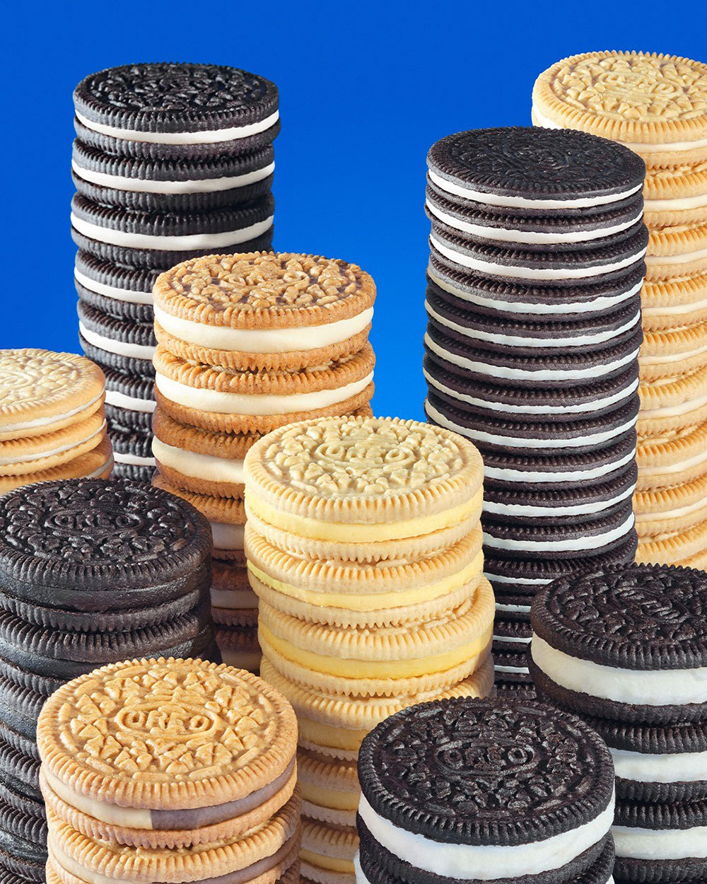 Towers of Oreos sorted by flavour on a blue background.