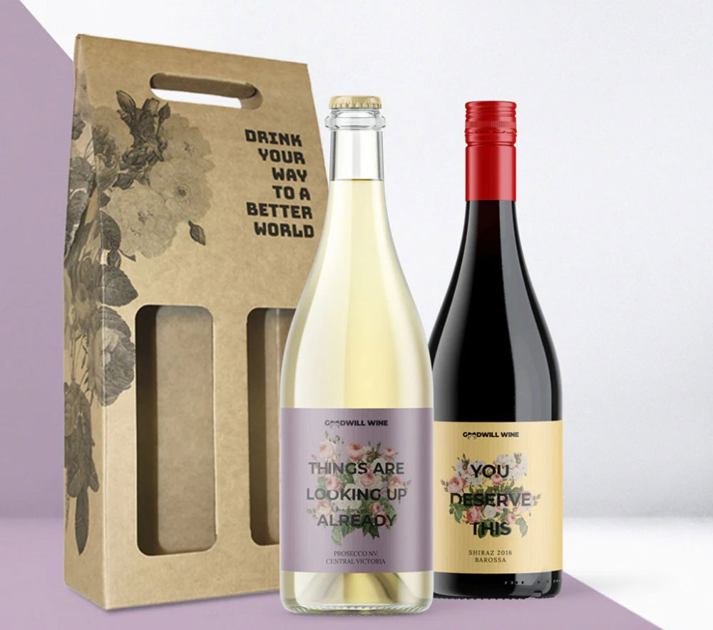 A bottle of red and white wine sit in front of a cardboard gift box that reads, 'Drink your way to a better world'.