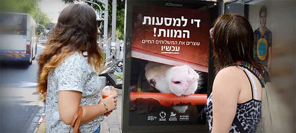 Two women looking at billboard against live export in Israel