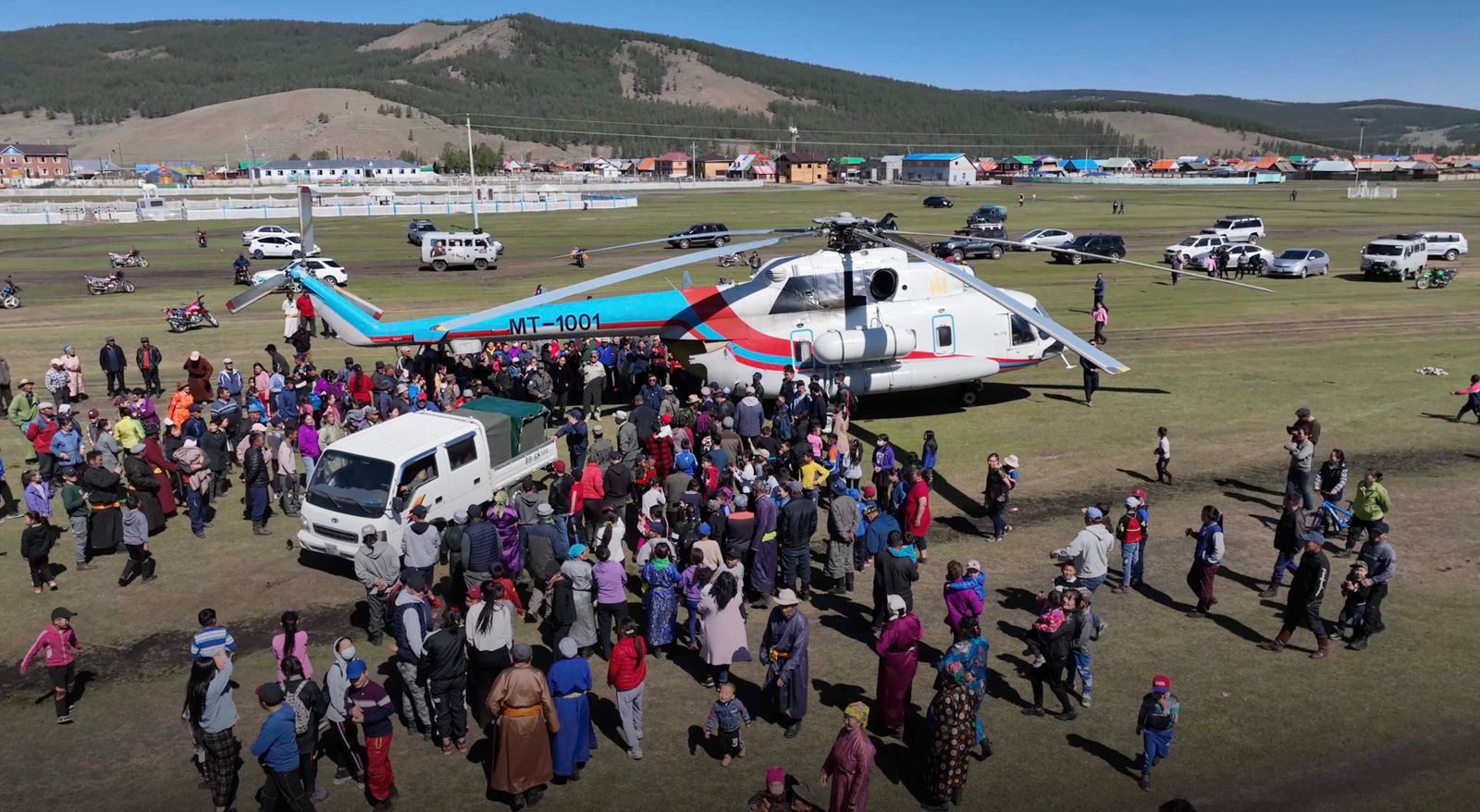 A drone image of a community of people in Mongolia surrounding the helicopter that will transport the bears to safety.