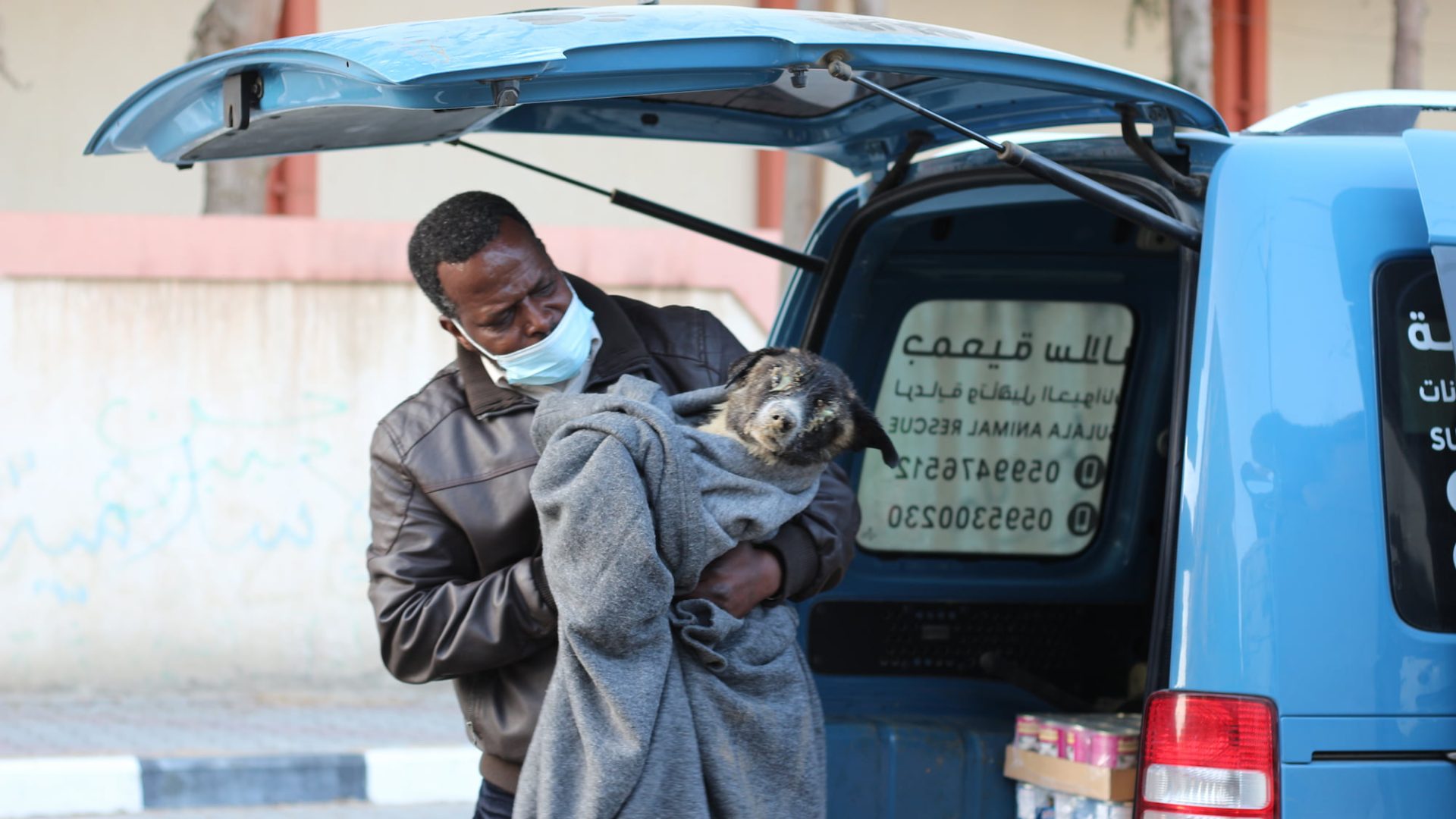 A dog wrapped in a blanket is being rescued by a Sulala team member.